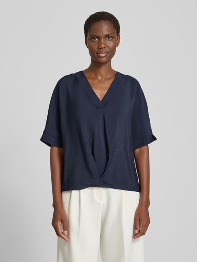 Frauenmodel trägt Blusenshirt mit V-Ausschnitt von Christian Berg Woman, locker geschnitten, dunkelblau, strukturierte Oberfläche, Ganzkörperansicht von vorne.