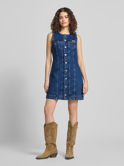 Vrouwenmodel draagt Regular Fit Minikleid in Denim-Optik mit Logo-Patch van Calvin Klein Jeans in blauw, katoen, mouwloos, ronde hals, borst- en steekzakken, voorkant volledig zichtbaar, geheelbeeld vooraanzicht.