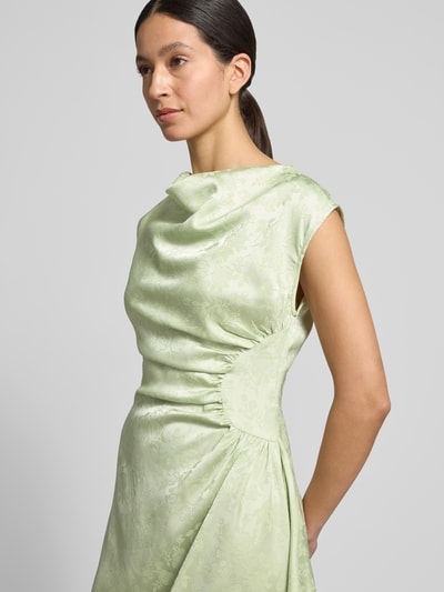Frauenmodel trägt figurumspielendes Midikleid mit seitlicher Raffung Modell 'WINNIE' von Vero Moda in hellgrün mit Allover-Muster, wasserfallartigem Ausschnitt, ärmellos, Nahtreißverschluss, Nahaufnahme Oberkörper.