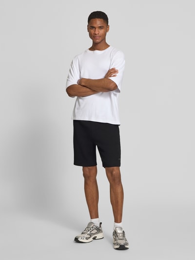 Männermodel trägt Regular Fit Sweatshorts aus Baumwoll-Mix Modell 'JT_GLOBE' von BOSS Green, schwarz, unifarben, Ganzkörperansicht von vorne.