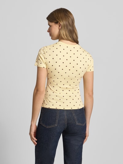 Frauenmodel trägt Slim Fit T-Shirt mit Rundhalsausschnitt Modell Joy von OH APRIL, Lyocell-Elasthan-Mix, Damen T-Shirt, Rückenlänge bei Größe S 50 cm, hellgelb mit braunen Punkten, Rückenansicht Ganzkörperansicht.