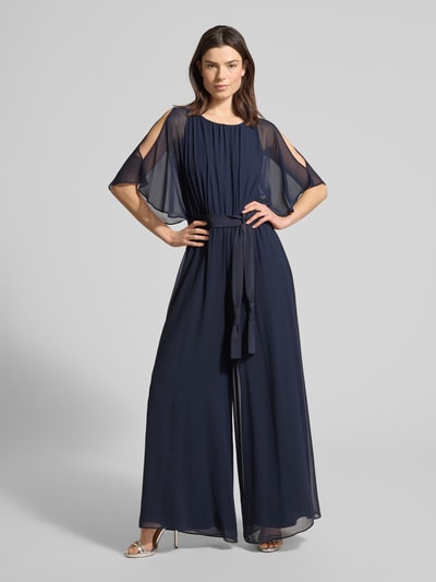 Frauenmodel trägt Jumpsuit aus fließendem Stoff mit Bindegürtel von Vera Mont in Dunkelblau, Chiffon, weites Bein, Ganzkörperansicht von vorne.
