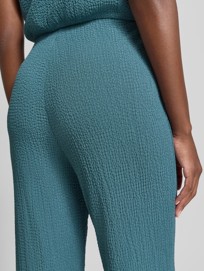 Frauenmodel trägt Hose mit Strukturmuster von Christian Berg Woman in Blaugrün, Material-Mix mit Stretch-Anteil, Nahaufnahme Oberschenkel.