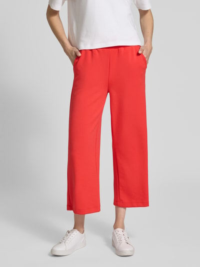 Frauenmodel trägt Wide Fit Sweatpants in verkürzter Passform Modell 'Banu' von Soyaconcept in leuchtendem Rot, Elastischer-Material-Mix mit Modal-Anteil, Schlupfhosen-Design und elastischem Bund mit Tunnelzug, Ganzkörperansicht von vorne.
