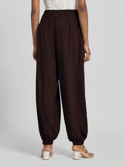 Frauenmodel trägt Balloon Fit Stoffhose aus Viskose-Mix Modell 'Hamy' von FREE/QUENT in Dunkelbraun mit elastischem Bund und Beinabschlüssen, Ganzkörperansicht Rückansicht.