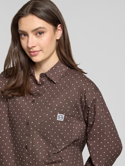 Frauenmodel trägt Relaxed Fit Bluse im Allover-Look Modell 'FRIDA' von Noisy May, braunes Material mit weißen Punkten, Nahaufnahme Oberkörper.