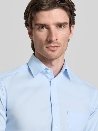 Männermodel trägt Modern Fit Business-Hemd mit Knopfleiste van OLYMP in lichtblauw, katoen, Kentkraag, borstzak, label-stiksel, Nahaufnahme Oberkörper.