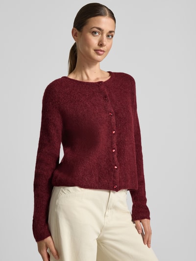 Frauenmodel trägt Strickjacke aus Alpaka-Mix von MOS MOSH in Dunkelrot mit geripptem Rundhalsausschnitt und Knopfleiste, lockere Passform, Ganzkörperansicht von vorne.