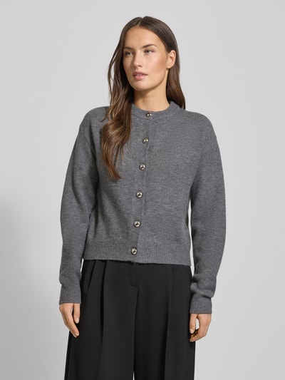 Frauenmodel trägt Cardigan mit Rundhalsausschnitt Modell 'FELIPE' von Mango, Material-Mix mit Woll-Anteil, gerader Schnitt, Knopfverschluss, Rückenlänge 52 cm in Größe S, Ärmellänge 58 cm, Farbe Grau, weiche Textur, Ganzkörperansicht von vorne.