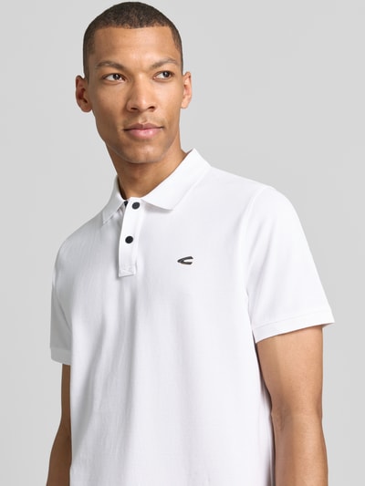 Męski model nosi Regular Fit Poloshirt in unifarbenem Design od camel active, bawełna z elastanem, gładka faktura, logo, zapięcie na guziki, zdjęcie z przodu, zbliżenie na górną część ciała.