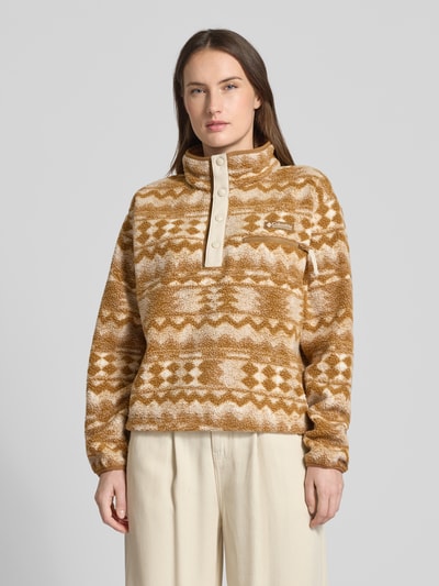 Modelka nosi Regular Fit Pullover mit Logo-Patch Modell 'Helvetia' von Columbia, beżowy, wzór w jodełkę, fason krój regular fit, materiał o fakturze polaru, elastyczne mankiety, stójka, kieszeń na piersi na zamek, widok całej sylwetki z przodu, długość pleców w rozmiarze S 55 cm, szerokość w rozmiarze S 44 cm (ramiona), szerokość w rozmiarze S 58 cm (biust), długość rękawa w rozmiarze S 58 cm.