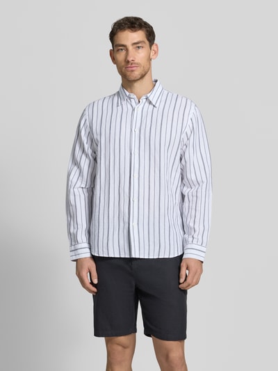 Mannenmodel draagt Regular Fit Leinenhemd aus Baumwoll-Leinen-Mix Modell 'CLAY' van SELECTED HOMME met allover streeppatroon, Kentkraag, lange mouwen, verstelbare 1-knoop manchet, wit met zwarte strepen, katoen-linnen-mix. Vooraanzicht hele lichaam.