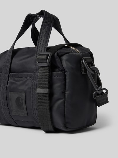 Produktfoto, Tasche mit Logo-Patch Modell 'Otis' von Carhartt Work In Progress in Schwarz, glatte Textur, Sicht auf Reißverschluss und Schulterriemen, Hauptfach mit Reißverschluss, abnehmbare Schulterriemen, Steckfächer, Maße 17x17x9 cm, Schulterriemen 92 cm
