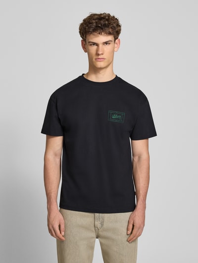 Männermodel trägt Regular Fit T-Shirt mit Logo-Print von BLKVIS aus Reine Baumwolle, dunkle Farbe, Rundhalsausschnitt, Ganzkörperansicht von vorne. Rückenlänge bei Größe M: 67 cm.