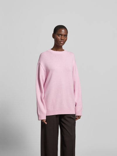 Frauenmodel trägt Oversized Wollpullover aus Woll-Mix von Nanushka in Rosa, Strick-Optik, Stehkragen, gerippte Abschlüsse, Rückenlänge 61 cm bei Größe S, Ganzkörperansicht von vorne.
