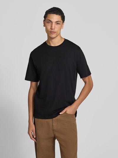 Männermodel trägt T-Shirt mit Rundhalsausschnitt Modell 'ORGANIC' von JACK & JONES in Schwarz zu brauner Hose, reine Baumwolle, gerader Schnitt, Nahaufnahme Oberkörper. Rückenlänge bei Größe M: 68 cm.