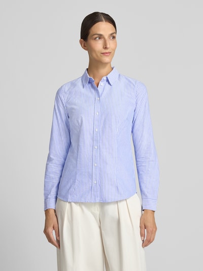 Frauenmodel trägt Hemdbluse aus reiner Baumwolle von Christian Berg Woman, taillierte Passform in Hellblau mit weißen Streifen, Ganzkörperansicht von vorne.