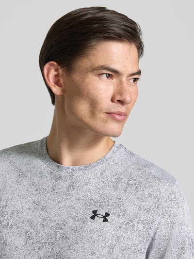 Männermodel trägt Regular Fit Sport-T-Shirt mit Strukturmuster Modell 'Pixelate' von Under Armour in Grau mit schwarzem Logo, Nahaufnahme Oberkörper, Herren Sport-T-Shirt von Under Armour.