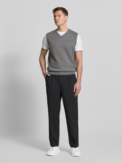 Männermodel trägt Pullunder mit Label-Stitching von Fynch-Hatton in Grau, aus reiner Baumwolle, Regular-Fit, mit V-Ausschnitt und gerippten Abschlüssen, Rückenlänge bei Größe M 66 cm, Ganzkörperansicht von vorne.