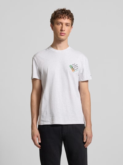 Männermodel trägt Regular Fit T-Shirt aus reiner Baumwolle von Tommy Jeans in Weiß mit Label Print, Rundhals, gerade Kurzarm, Ganzkörperansicht von vorne.