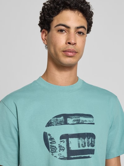Männermodel trägt Regular Fit T-Shirt mit Logo-Print Modell 'icon' von G-Star Raw in Hellblau, reine Baumwolle, Nahaufnahme Oberkörper.