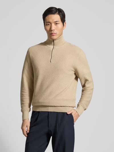 Männermodel trägt Regular Fit Troyer aus reiner Baumwolle Modell 'H-ULICIO' von BOSS in beige Strickoptik mit kurzem Reißverschluss, Ganzkörperansicht von vorne.