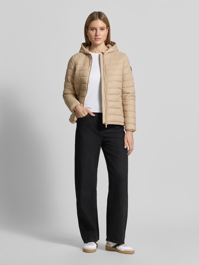 Vrouwenmodel draagt gewatteerd jack met capuchon model 'THELMA' van CARS JEANS, regular fit, ritssluiting, steekzakken, kleur beige, ganzebodyvooraanzicht. Ruglengte maat S 61 cm, schouderbreedte 39 cm, borstwijdte 50 cm, mouwlengte 62 cm.