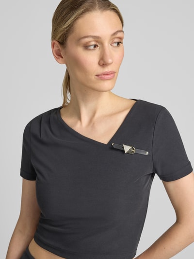 Frauenmodel trägt T-Shirt mit asymmetrischem Ausschnitt Modell 'KAROLE' von GUESS, Schwarz, Slim Fit, Cropped, Nahaufnahme Oberkörper.