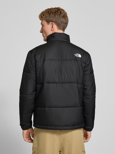 Männermodel trägt Regular Fit Jacke in Stepp-Optik Modell 'NUKETO' von The North Face in Schwarz, Rückenansicht, Kontext: Herren Jacke, Stehkragen, Logo-Print, Napoleontasche, Maße bei Größe M