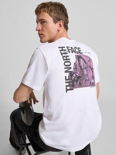Männermodel trägt Regular Fit T-Shirt mit Logo-Print von The North Face aus Baumwoll-Mix, weiß mit lila Print, Rückenlänge 69 cm, Ganzkörperansicht Rückansicht.
