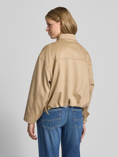 Frauenmodel trägt Jacke in Leder-Optik mit Reißverschluss und Eingrifftaschen von Gina Tricot, Relaxed-Fit, Material-Mix, Rückenlänge 52 cm, Schulterbreite 52 cm, Brustweite 56 cm, Ärmellänge 50 cm, beige Farbe, glatte Textur, Ganzkörperansicht Rückansicht.