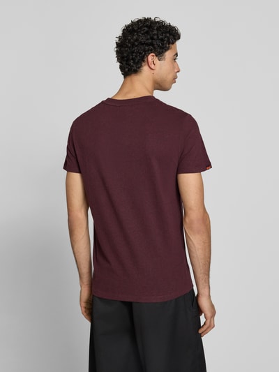 Männermodel trägt Regular Fit T-Shirt mit Logo-Stitching von Superdry in Dunkelrot aus Reine Baumwolle, Rückenlänge 69 cm, Ganzkörperansicht Rückansicht.