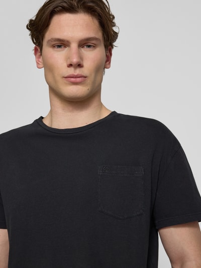 Mężczyznamodel nosi T-Shirt aus Baumwoll-Leinen-Mix mit Brusttasche od Superdry, czarny, okrągły dekolt, krój regular fit, brustasza, długość tyłu w rozmiarze M: 66 cm, mieszanka bawełny i lnu, męski t-shirt, zbliżenie na górną część ciała z przodu.