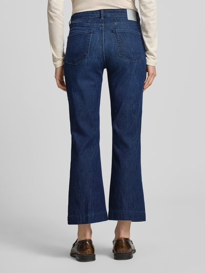 Frauenmodel trägt Bootcut Jeans im 5-Pocket-Design Modell 'Mary' von Brax aus dunkelblauem Baumwoll-Mix, Label-Detail, Ganzkörperansicht Rückansicht.