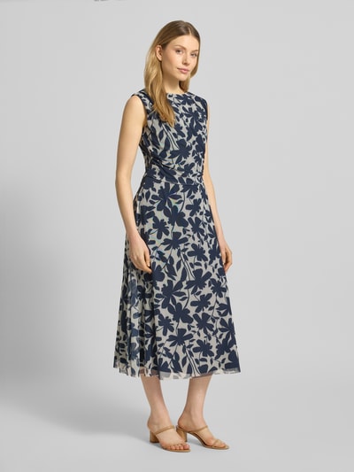 Modelka nosi Regular Fit Midikleid mit floralem Allover-Print od Swing, ciemnoniebiesko-biały wzór kwiatowy, okrągły dekolt, bez rękawów, marszczenia, ukryty zamek, podszewka, elastyczny materiał, krój regular fit, długość pleców w rozmiarze 36: 126 cm, szerokość w rozmiarze 36: 47 cm, widok całej sylwetki z przodu