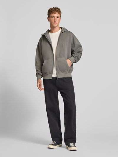 Männermodel trägt Regular Fit Sweatjacke aus Baumwoll-Mix von PEGADOR in Grau mit Logo-Stickerei, Kängurutasche, Zipper, Ganzkörperansicht von vorne.