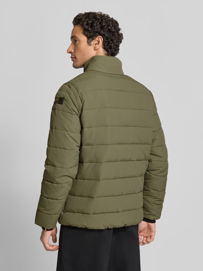 Męski model nosi Steppjacke mit Brusttaschen Modell 'SKYLOCK' od PME Legend, kolor oliwkowy, poziome przeszycia, krój regular fit, stójka, kieszenie na piersi, detal z logo, widok całej sylwetki od tyłu, długość tyłu w rozmiarze M: 70 cm, szerokość ramion w rozmiarze M: 47 cm, szerokość w rozmiarze M: 59 cm, długość rękawa w rozmiarze M: 68 cm.