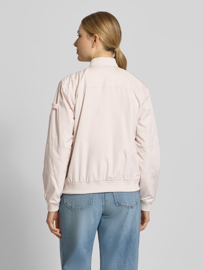 Frauenmodel trägt Regular Fit Bomberjacke mit Stehkragen Modell 'Brooklyn' von Frieda & Freddies in Hellrosa, glatte Textur, elastische Abschlüsse, Eingrifftaschen und Reißverschluss, kombiniert mit blauen Jeans, Rückansicht, Ganzkörperansicht. Rückenlänge bei Größe 36: 59 cm, Schulterbreite: 44 cm, Brustweite: 52 cm, Ärmellänge: 51 cm.