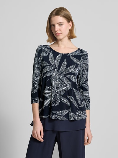 Frauenmodel trägt Blusenshirt mit rückseitigem Schlüsselloch-Ausschnitt von Vera Mont im Material-Mix mit Stretch-Anteil, gerader Schnitt, Rundhalsausschnitt, 3/4-Arm, florales Muster in Dunkelblau und Weiß, Damen, Ganzkörperansicht von vorne. Rückenlänge bei Größe 36: 57 cm.