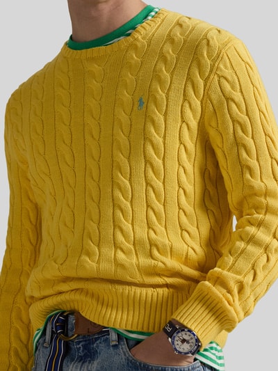 Męski model nosi Regular Fit Strickpullover aus reiner Baumwolle od Polo Ralph Lauren, żółty, wzór w warkocze, crew neck, bawełna, detal logo, widok na górną część ciała z przodu.