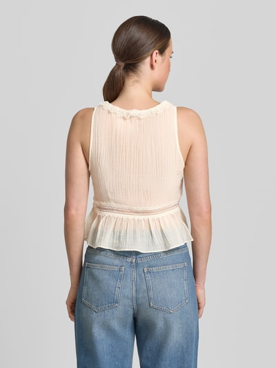 Frauenmodel trägt Top aus Lyocell-Mix mit Zierschleifen Modell 'Elena' von Mango in Beige, taillierte Passform, Loch-Stitching, Ganzkörperansicht Rückansicht.
