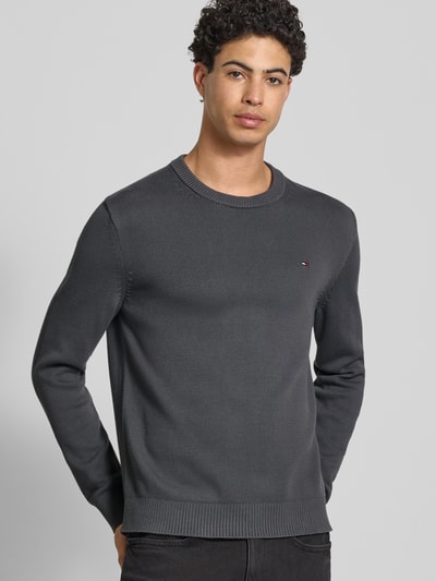 Męski model nosi Regular Fit Strickpullover aus reiner Baumwolle od Tommy Jeans, kolor jednolity, krój regular fit, logo, okrągły dekolt, długi rękaw, ściągacze, bawełna; ujęcie: z przodu, górna część ciała.
