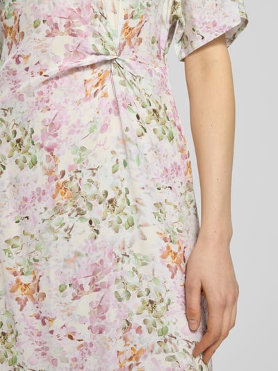 Frauenmodel trägt Midikleid aus Viskose Modell 'Dela2' von JOOP! mit floralem Pastellmuster und Drapierung, Nahaufnahme Oberkörper.