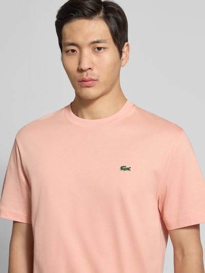 Männermodel trägt Regular Fit Poloshirt aus reiner Baumwolle von Lacoste, Optik: Unifarben, Logo-Stitching, Rundhals, Kurzarm, Nahaufnahme Oberkörper.