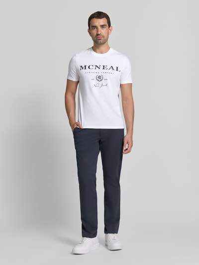 Męski model nosi T-Shirt mit Label-Print und Rundhalsausschnitt od MCNEAL, biała bawełna, krój regular fit, długość tyłu w rozmiarze M: 68 cm, całkowity widok z przodu.