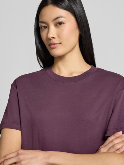 Vrouwenmodel draagt t-shirt uit puur katoen van Stefanel in auberginekleur, los model, ronde hals, ruglengte maat S 62 cm, detailopname bovenlichaam.