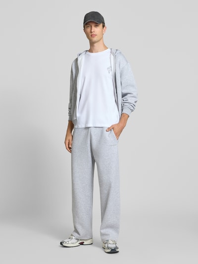 Männermodel trägt Relaxed Fit T-Shirt aus reiner Baumwolle Modell "DYLAN" von JACK & JONES in Weiß mit Print-Detail, Ganzkörperansicht von vorne.