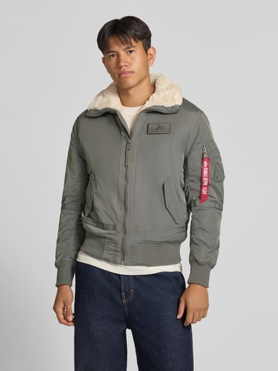 Männermodel trägt Bomberjacke mit Label-Patch und Kentkragen von Alpha Industries in Olivgrün mit Teddyfellkragen, Reißverschluss, Eingrifftaschen, Regular Fit, Nahaufnahme Oberkörper