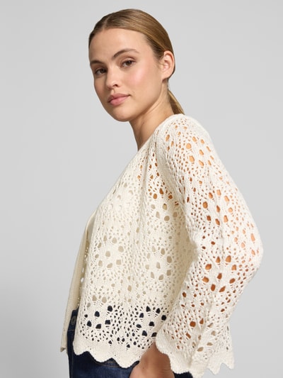 Kobieta modelka nosi Relaxed Fit Strickjacke in Lochstrick-Optik od Betty Barclay, półprzezroczysty materiał, rękaw o dł. 3/4, długość tyłu 50 cm, długość rękawów 54 cm, kremowy kolor, ażurowy wzór, zbliżenie na górną część ciała z przodu.