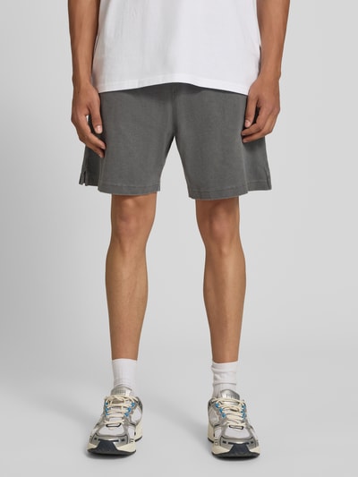 Männermodel trägt Regular Fit Shorts mit elastischem Bund Modell 'Harper' von Carhartt Work In Progress aus Reine gewachste Baumwolle, Grauton, glatte Textur, Herren Shorts, Ganzkörperansicht von vorne.